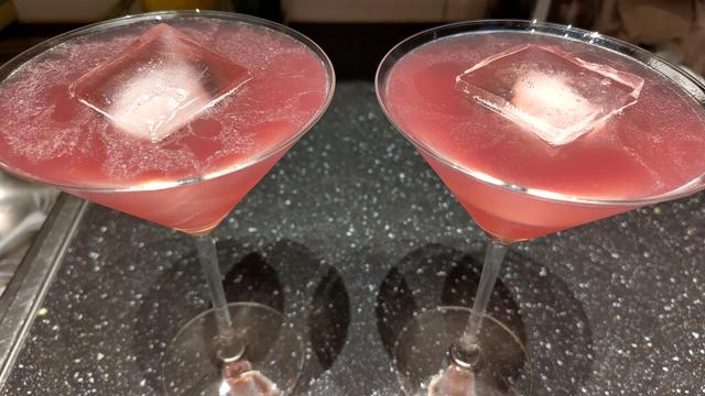 Två rosa drinkar med is som står på en diskbänk.