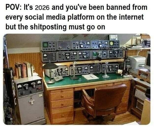 Text: "POV: It's 2026 and you've been banned from every social media platform on the internet but the shitposting must go on." Under ett skrivbord fullproppat med radioutrustning.