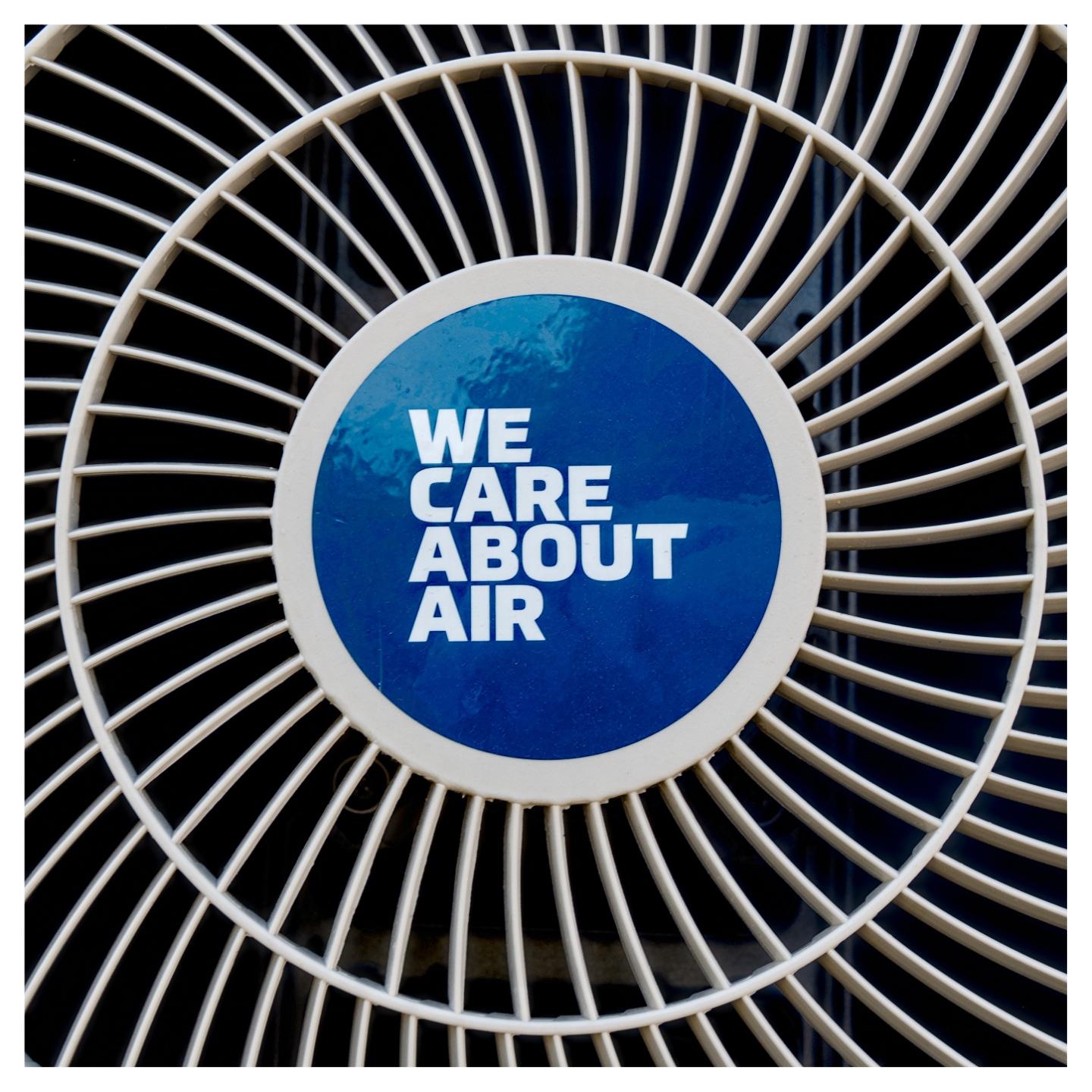En fyrkantig bild på en fläkt med vit text på blå bakgrund "WE CARE ABOUT AIR".