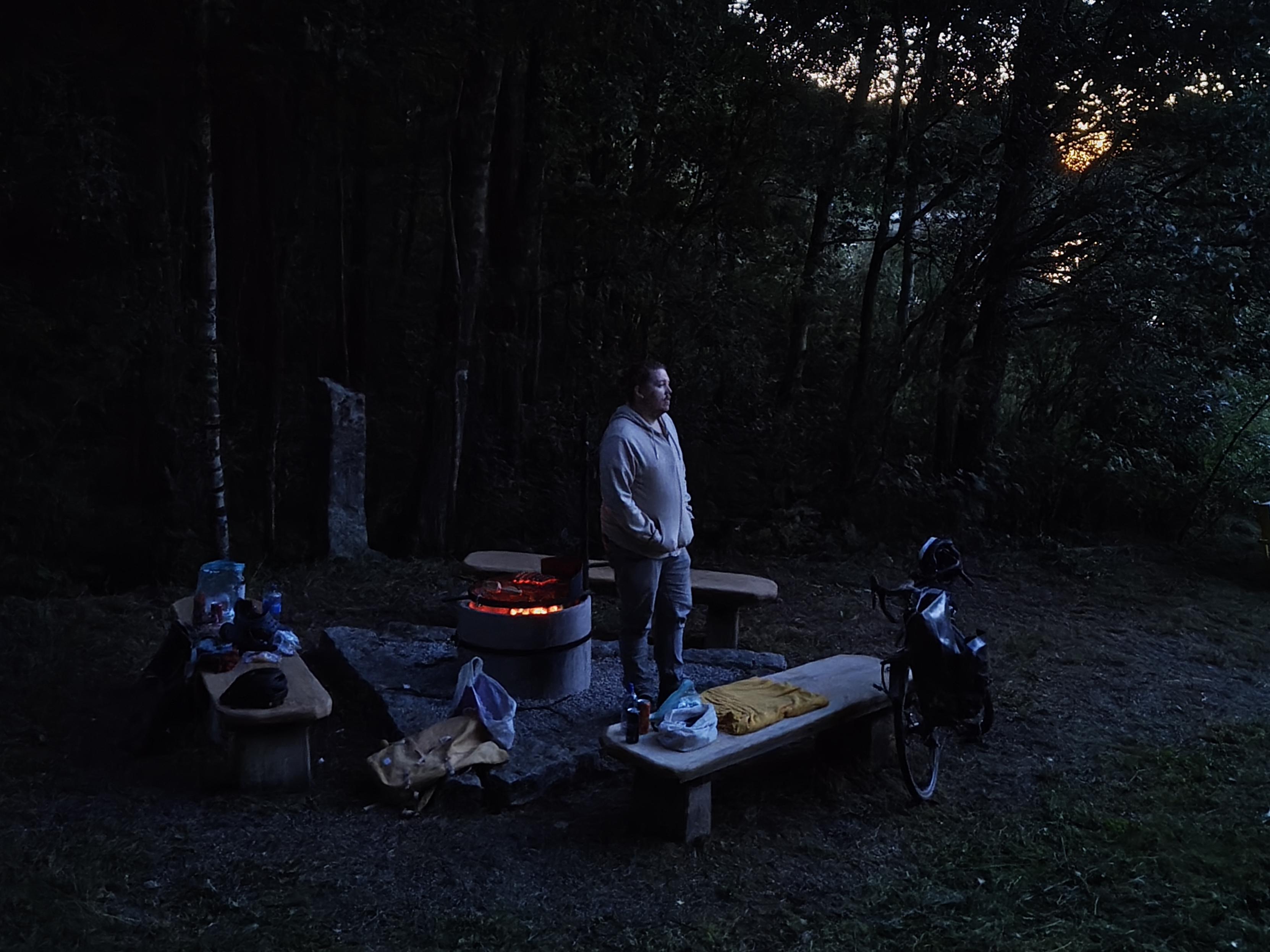 min kompis står vid grillen i mörkret
